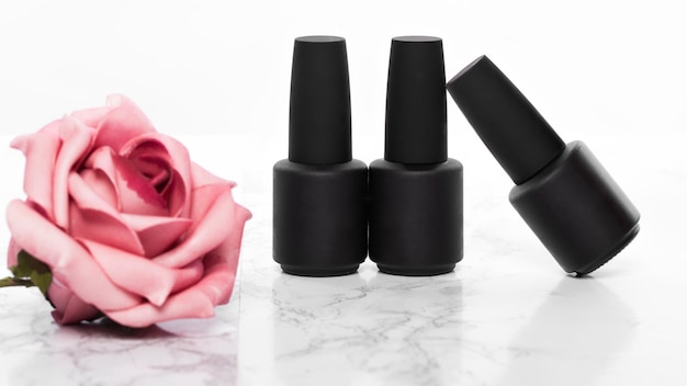 Botellas negras de esmalte de uñas sobre un fondo de flores Diseño de manicura