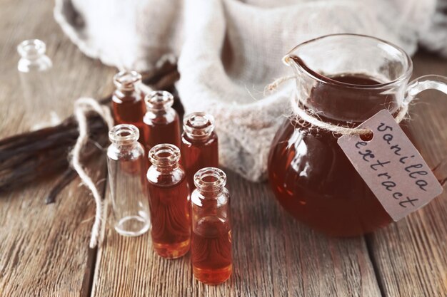 Botellas pequeñas y jarra con extracto de vainilla aromática en la mesa