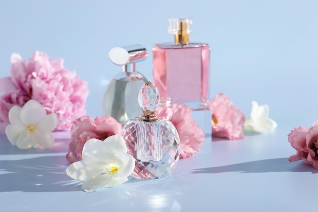 Botellas de perfumes de lujo y decoración floral sobre un fondo gris claro