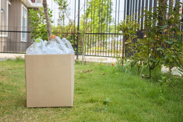 Botellas de plástico en la caja de basura de reciclaje marrón sobre la hierba verde