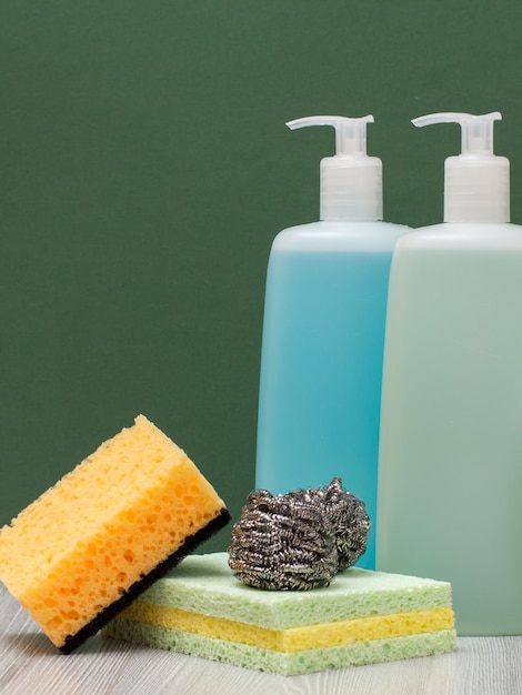 Botellas de plástico de detergente para hornos microondas y estufas, limpiador de vidrios y azulejos y esponjas en fondo verde. Productos de lavado y limpieza.