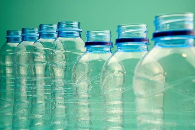 Botellas de plástico en fila sobre un fondo verde