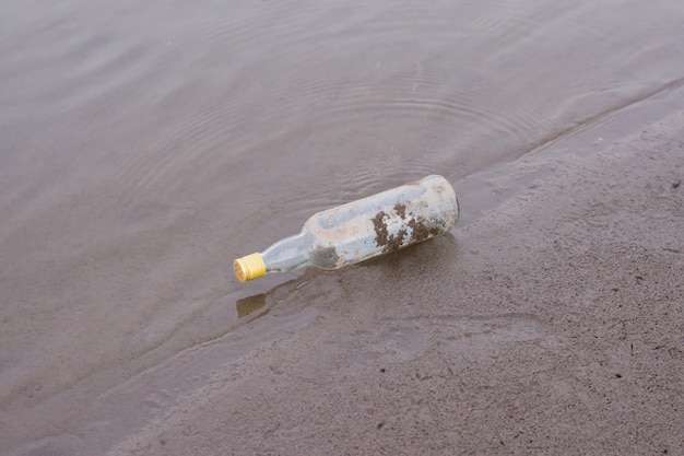 Botellas y residuos de basura en la orilla de un río.