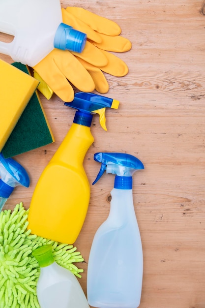 Botellas de spray de limpieza y composición plana de tela sobre un fondo de madera