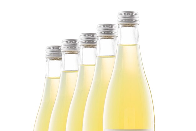 Botellas transparentes de limonada amarilla se colocan una detrás de la otra. Aislar.