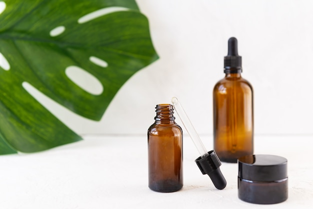 Botellas de vidrio para aceite cosmético con monstera.