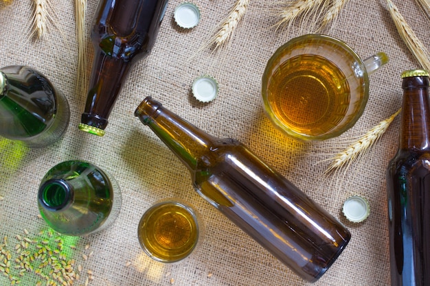 Botellas de vidrio. Jarra de vidrio y un vaso de cerveza. Espiguillas de trigo