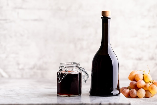 Foto botellas de vidrio originales con vinagre diferente sobre una mesa de mármol contra una mesa de una pared de ladrillo blanco. copie el espacio. horizontal.