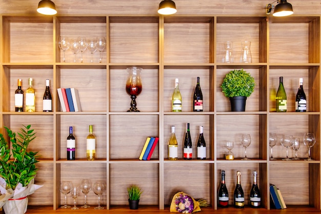 Foto botellas de vino blanco y tinto en un estante de madera con libros en el gabinete de la bodega privada.