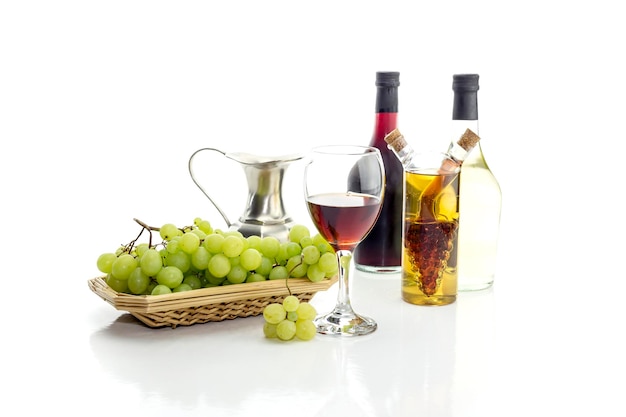 Botellas de vino jarra llena de uvas blancas y maduras en un primer plano de fondo blanco