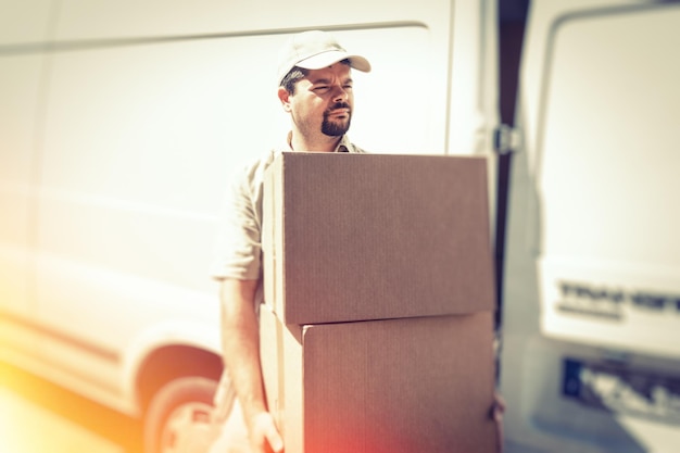 Boten mit einer Kartonbox, die an einem sonnigen Tag gegen einen LKW steht