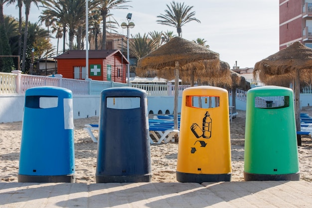 Botes de basura coloridos en la playa de la ciudad