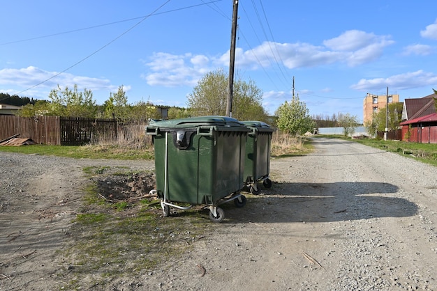 Botes de basura verdes en la carretera del pueblo