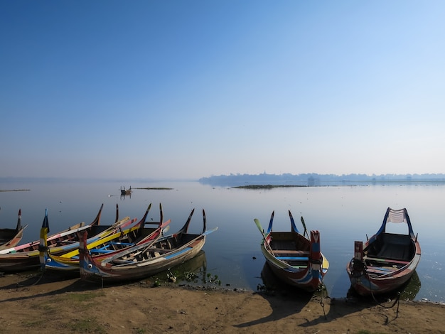 Foto botes de madera coloridos en la orilla del lago de aguas tranquilas y tranquilas con pájaros y cielo azul claro b