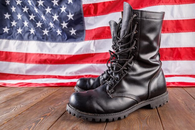 Botines negros frente a la bandera estadounidense en superficie de madera