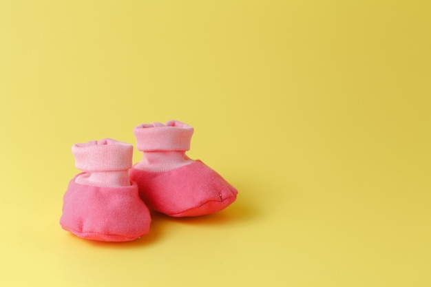 Foto botinhas de bebé numa superfície amarela