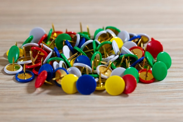 Botões de papelaria em forma de agulha closeup multicoloridos em um fundo de madeira