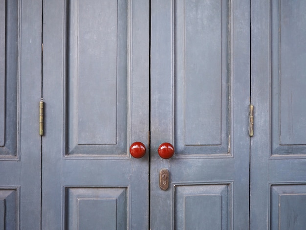 Botões vermelhos do vintage na porta de madeira cinza da casa retrô.