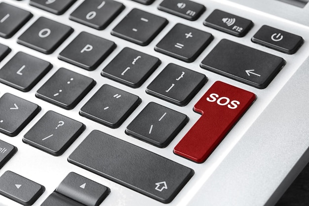 Botón rojo con la palabra SOS en el teclado de la computadora concepto de rescate de primer plano
