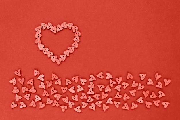 Foto botones de madera de corazón de coral en forma de corazones sobre un fondo de papel coral