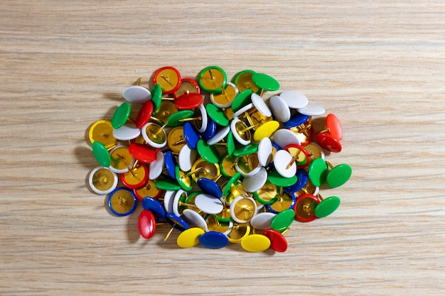 Botones de papelería en forma de aguja closeup multicolor sobre un fondo de madera