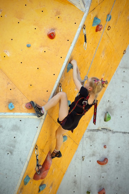 Bouldern, kleines Mädchen klettert die Wand hoch