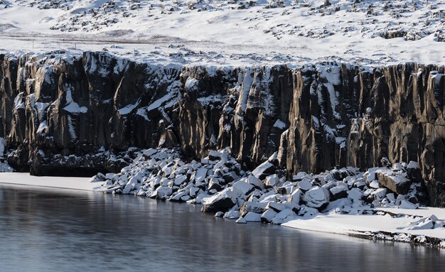 Boulderwürfel unter den Klippen mit Schnee und Fluss