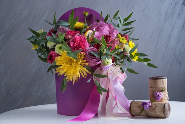 Bouqet de flores lilas con hortensias, rosas, santini y pascua. En mesa blanca.