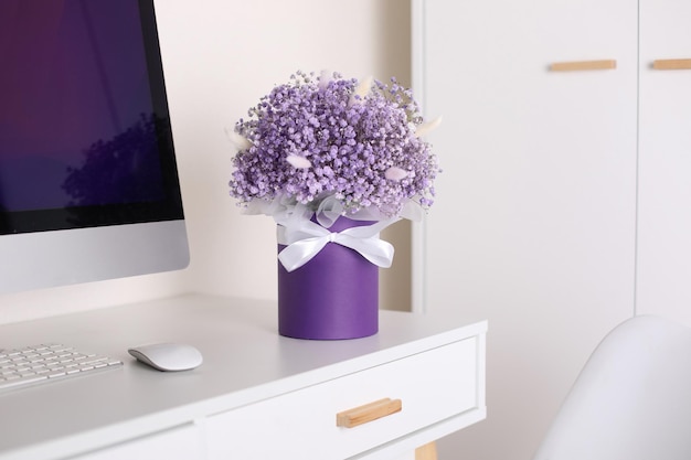 Foto bouquet aus schönen violetten blumen auf dem schreibtisch in der nähe des computers