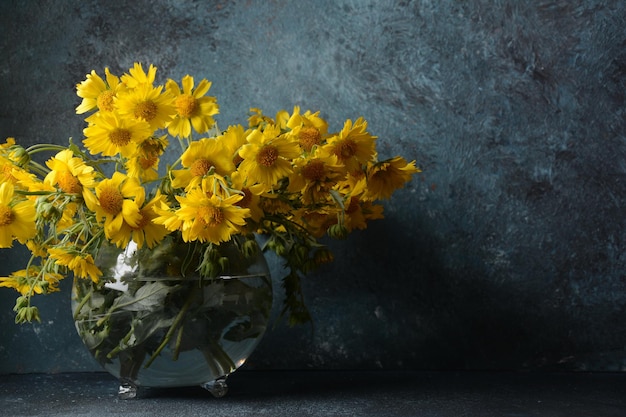 Bouquet de Doronicumflowers (família do girassol) em um vaso de flores de vidro transparente.