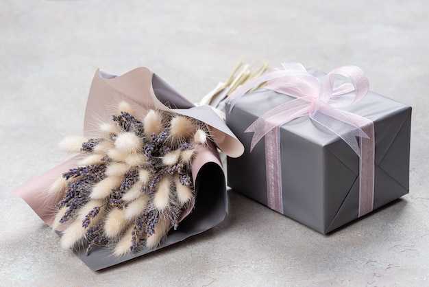 Bouquet de lavanda e lagurus com embalagem cinza-púrpura com uma caixa de presente em uma única cor.