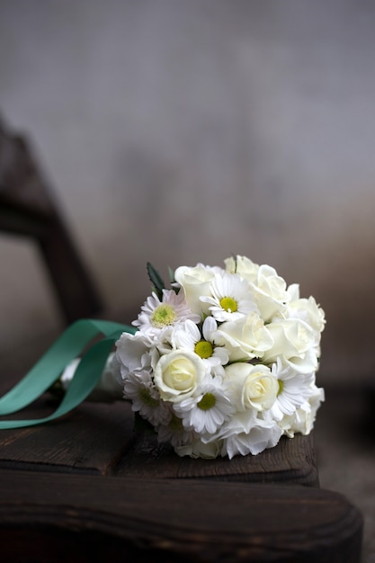 Bouquet de noiva de rosas brancas encontra-se em um banco de madeira