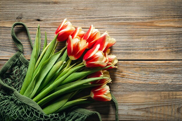 Bouquet de tulipas em saco de corda em um fundo de madeira conceito de vista superior do dia da mãe dia da mulher