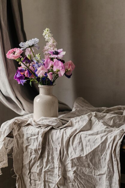 Bouquet elegante sobre un fondo de lino rústico hermosa anémona colorida ranunculus lathyrus scabiosa en jarrón flores de verano florales de mal humor naturaleza muerta espacio para el texto