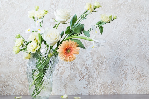 Bouquet en jarrón de vidrio sobre la mesa en la pared del fondo