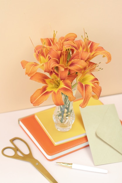 Bouquet de lirios naranjas con tijeras doradas y sobre artesanal.