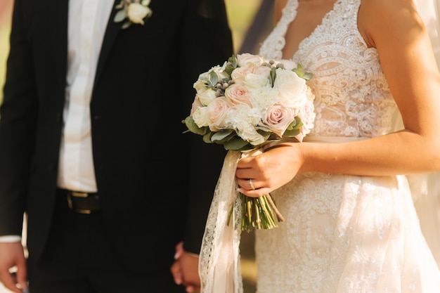 Bouquet nas mãos do noivo com a esposa no meio da celebração