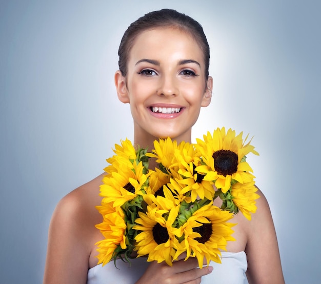 Bouquet para un retrato de estudio de belleza de una hermosa joven modelo posando sobre un fondo azul.