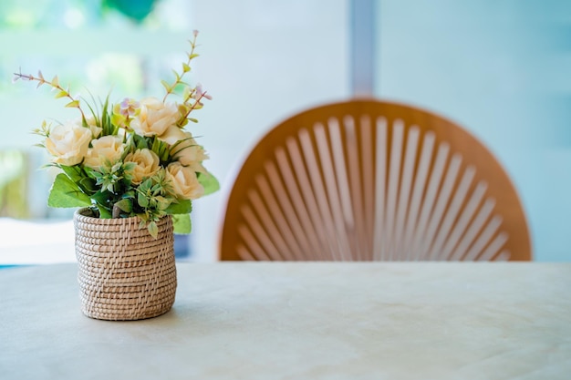 Foto bouquet vintage artificial de flores brancas em cesta de vime de pé à esquerda da mesa de madeira