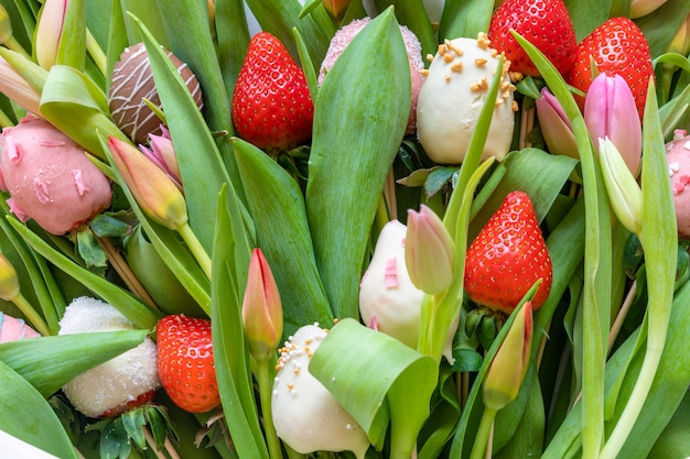 Bouquet von Erdbeeren und Tulpen mit Schokoladenüberzug auf grünem Hintergrund