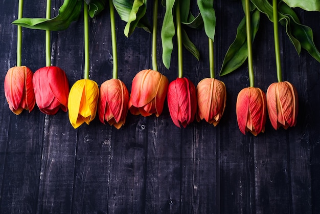 Foto bouquet von orange und gelben tulpen über einer rustikalen holztischplatte