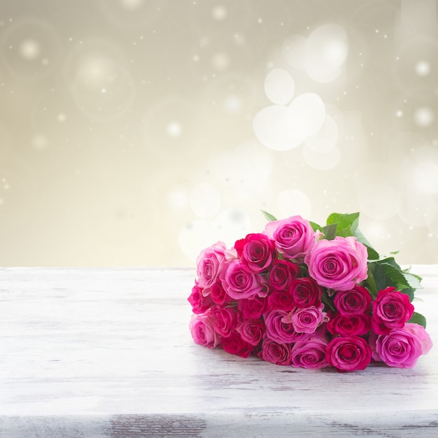 Bouquet von rosa und magenta frischen Rosen auf hölzernem Tischrand lokalisiert auf weißem Hintergrund