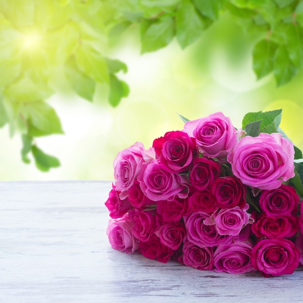 Bouquet von rosa und magentafarbenen frischen Rosen auf Tisch im Garten