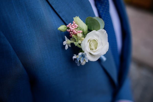 Boutonniere blanco anclado a la chaqueta azul del novio