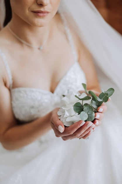 Boutonniere de bodas de flores en las manos de la novia Detalles de la boda El primer encuentro de la novio y la novia La novia está esperando al novio Retrato de la Novia