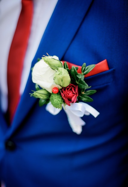 Boutonniere feito de rosas brancas e vermelhas colocar na jaqueta do noivo