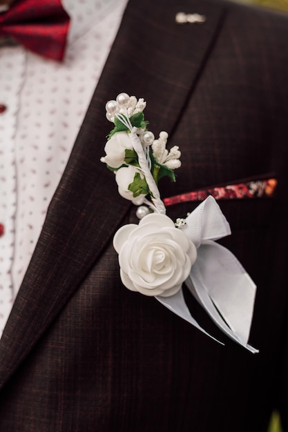 Boutonniere linda branca na jaqueta dos noivos