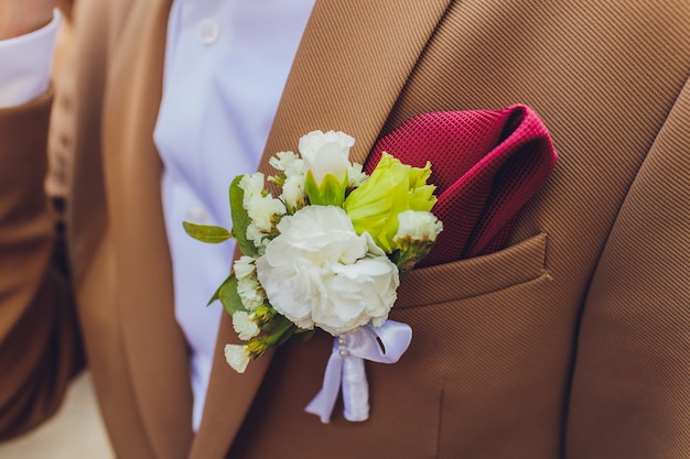 Boutonniere Pfingstrosen blühen auf blauer Anzugjacke des Hochzeitsbräutigams Nahaufnahme.