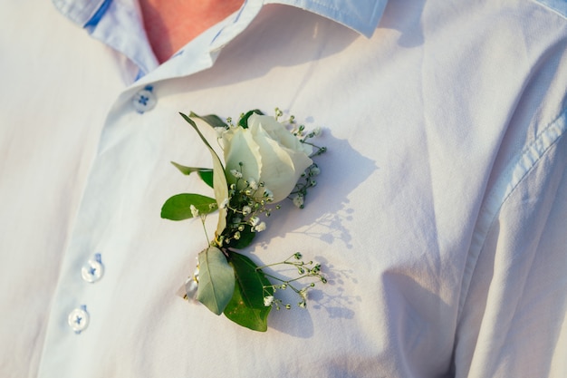 Boutonniere de una rosa blanca en la camisa de un novio