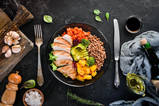 Foto bowl buddha buchweizenkürbis hähnchenfilet avocado karotten auf schwarzem hintergrund ansicht von oben freier platz für ihren text